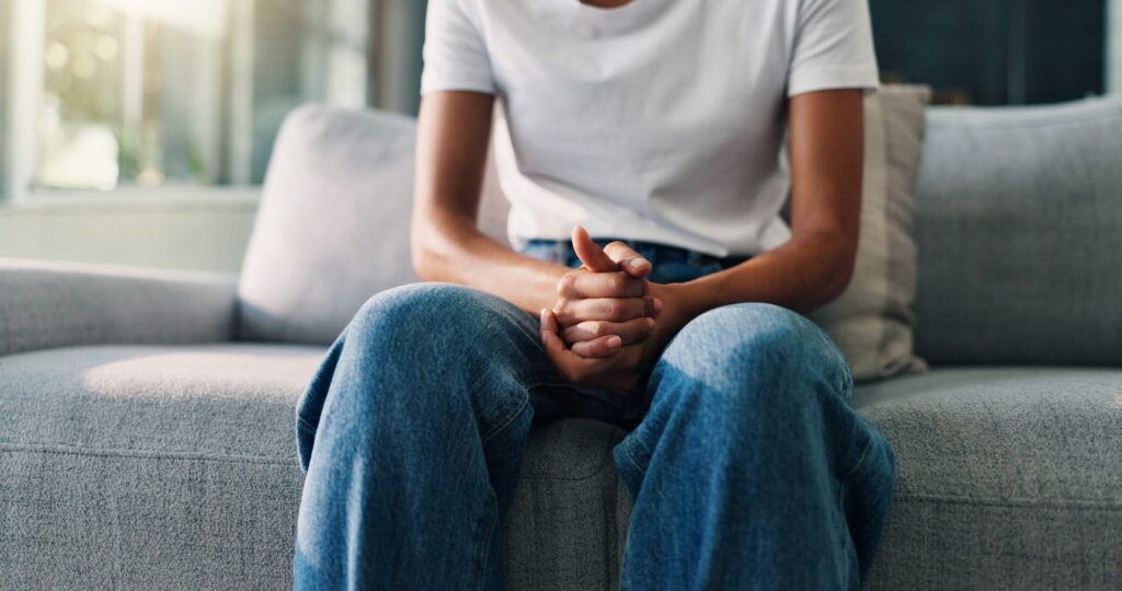 person anxiously sitting down on couch